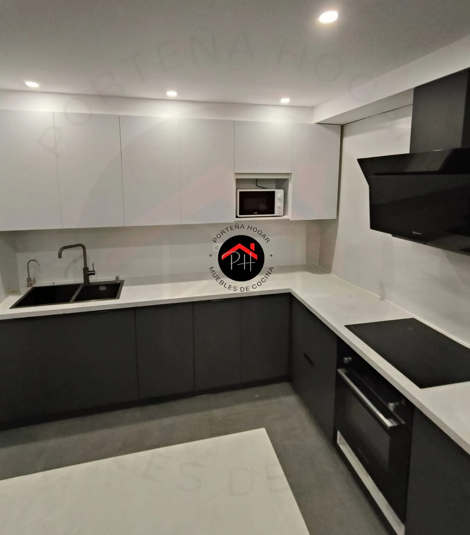 Cocina en L con muebles bajos grafito, altos claros, encimera blanca y fregadero y placa negros